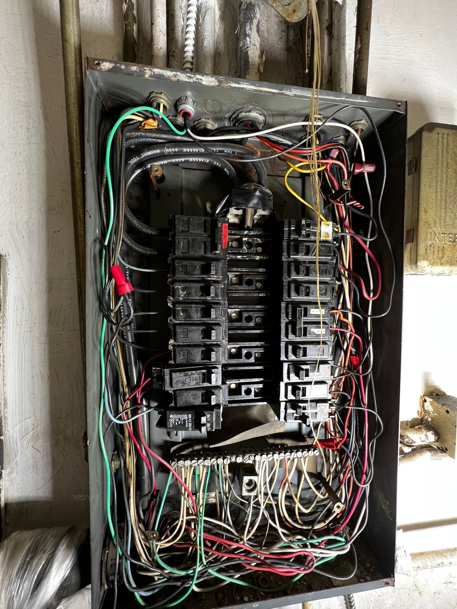 An open electrical breaker panel with numerous colorful wires connected to various switches inside a metal box.