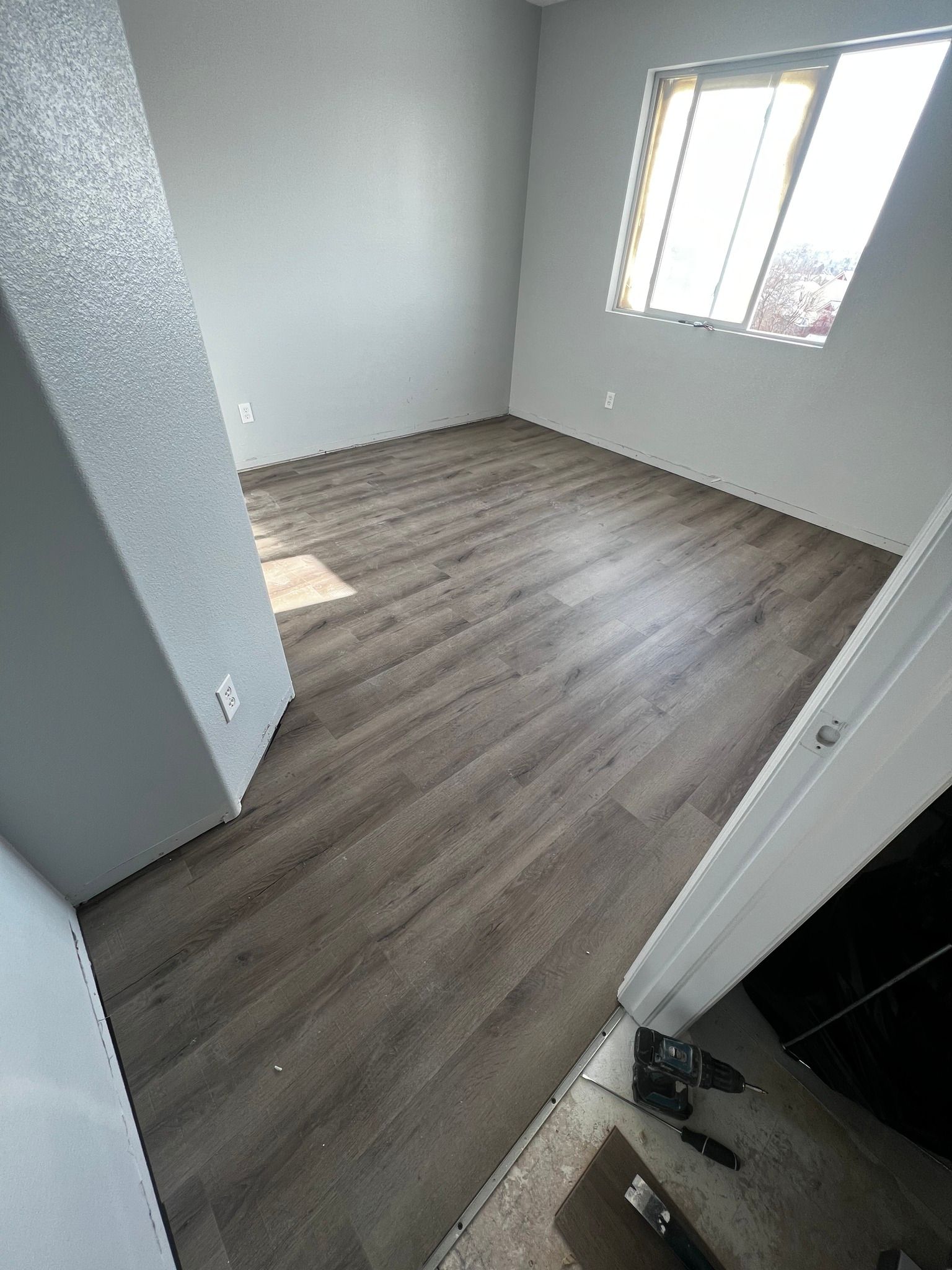 A view of a room with gray walls and installed wood-look laminate flooring, taken from the doorway.