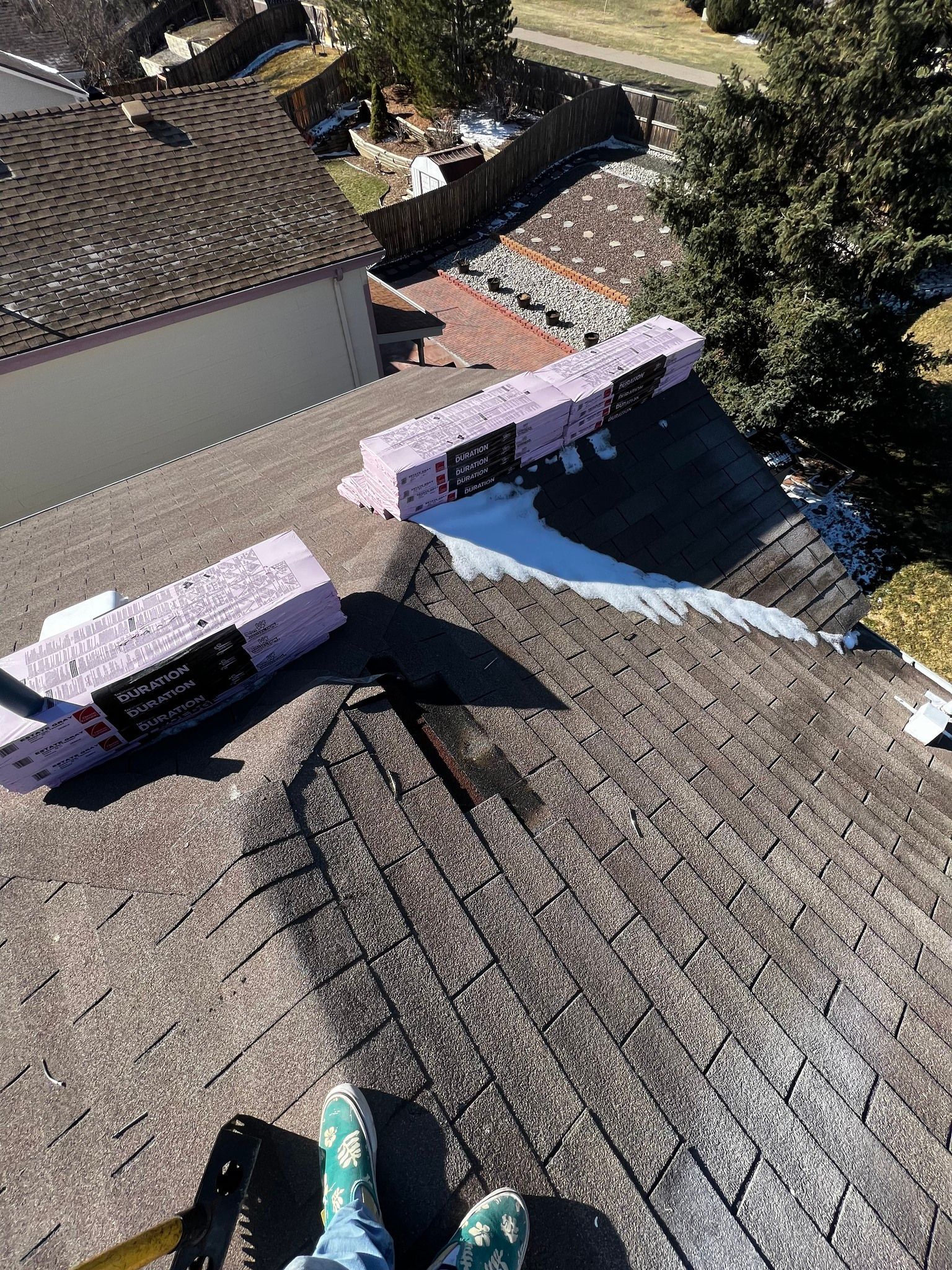 A rooftop view showing two pink foam blocks placed on shingles near a valley where white roof sealant has been applied.