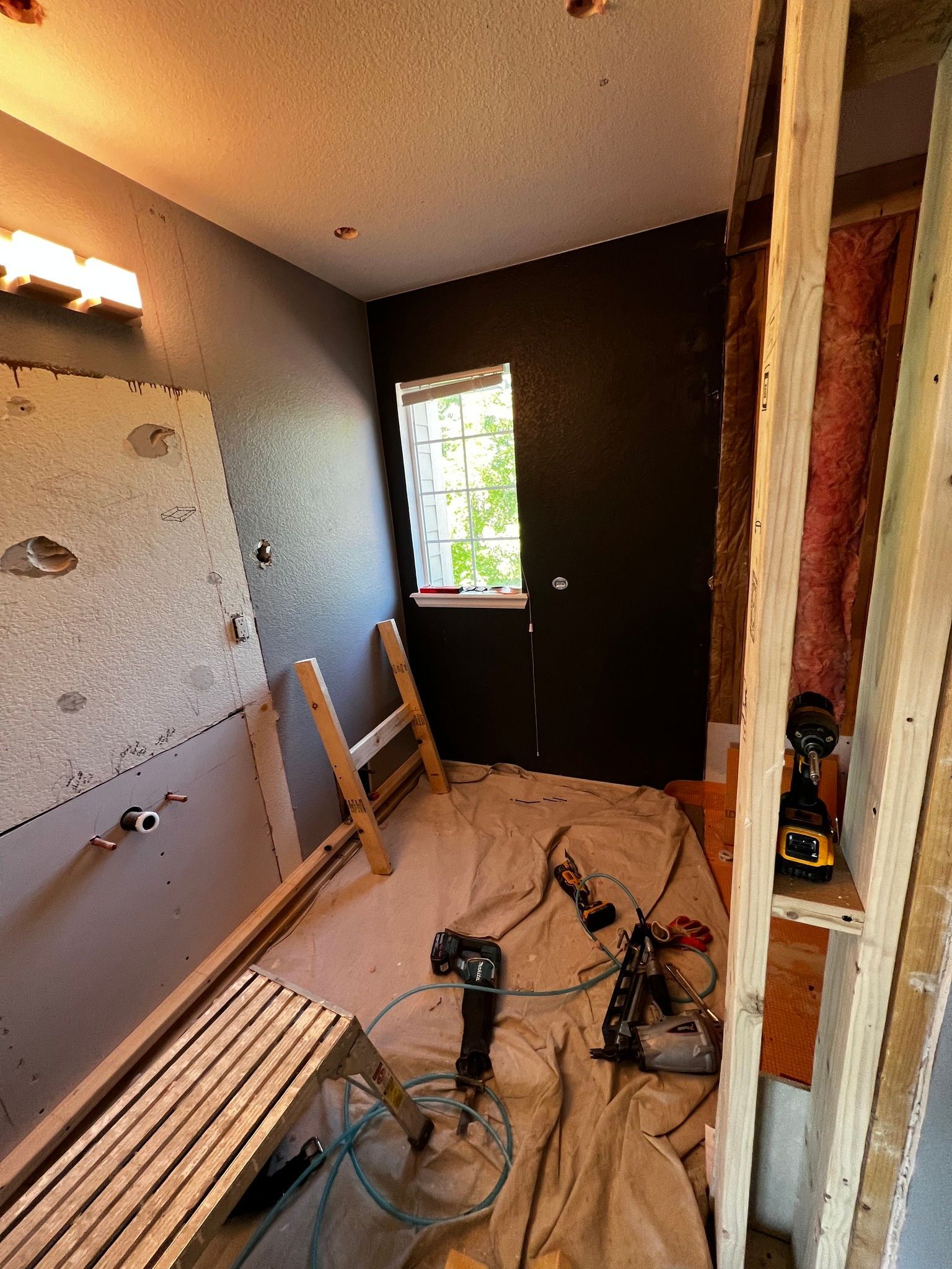 Renovated room with tools, tarps, and a ladder on the floor near a window and open doorway