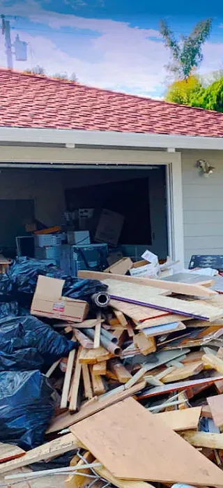 A pile of wood is in front of a house with a red roof.