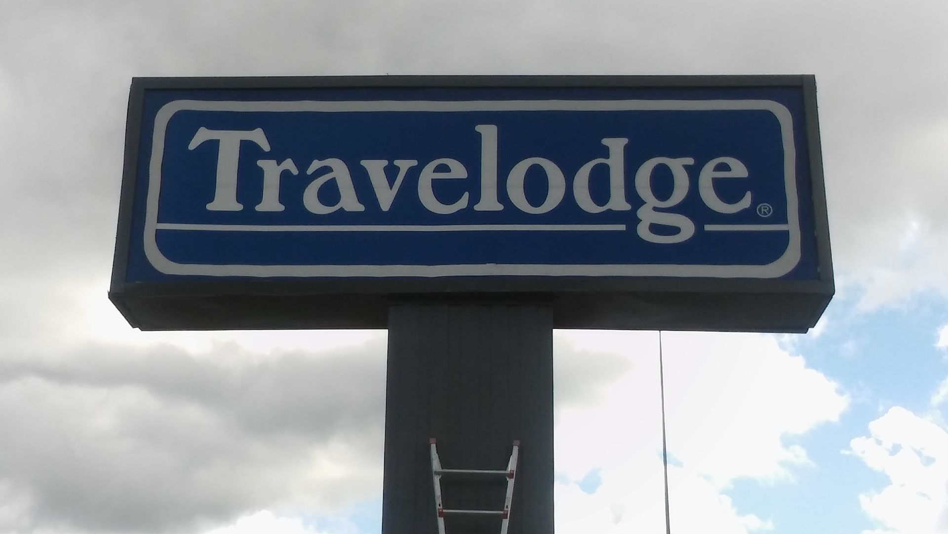 A travellodge sign is against a cloudy sky