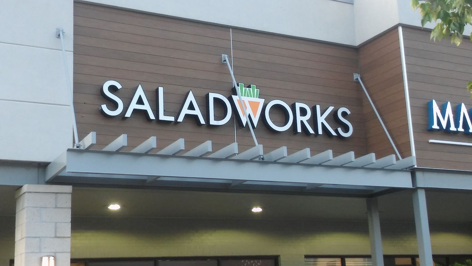 The front of a saladworks restaurant with a sign above it