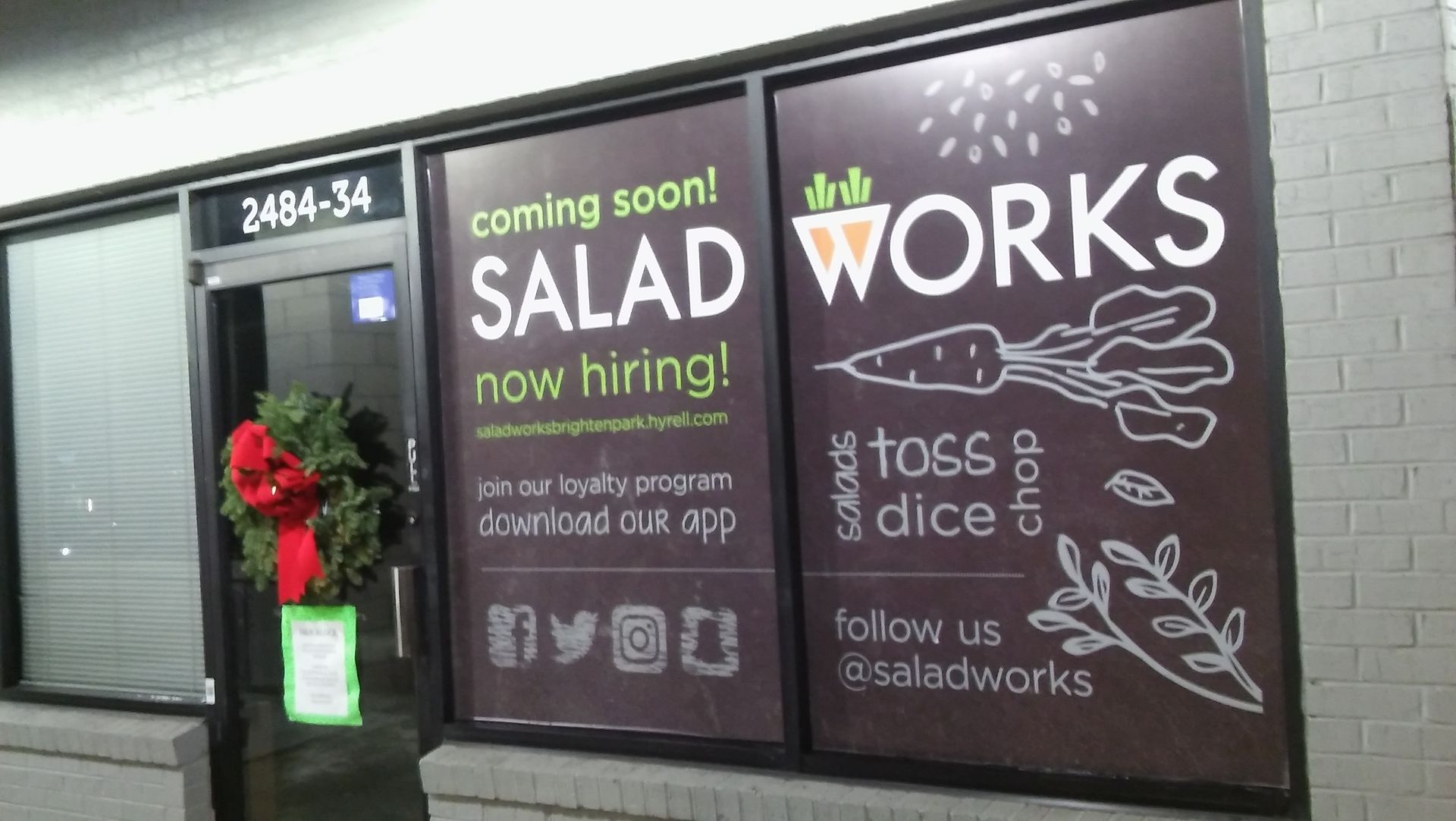 A sign on the side of a building that says salad works now hiring