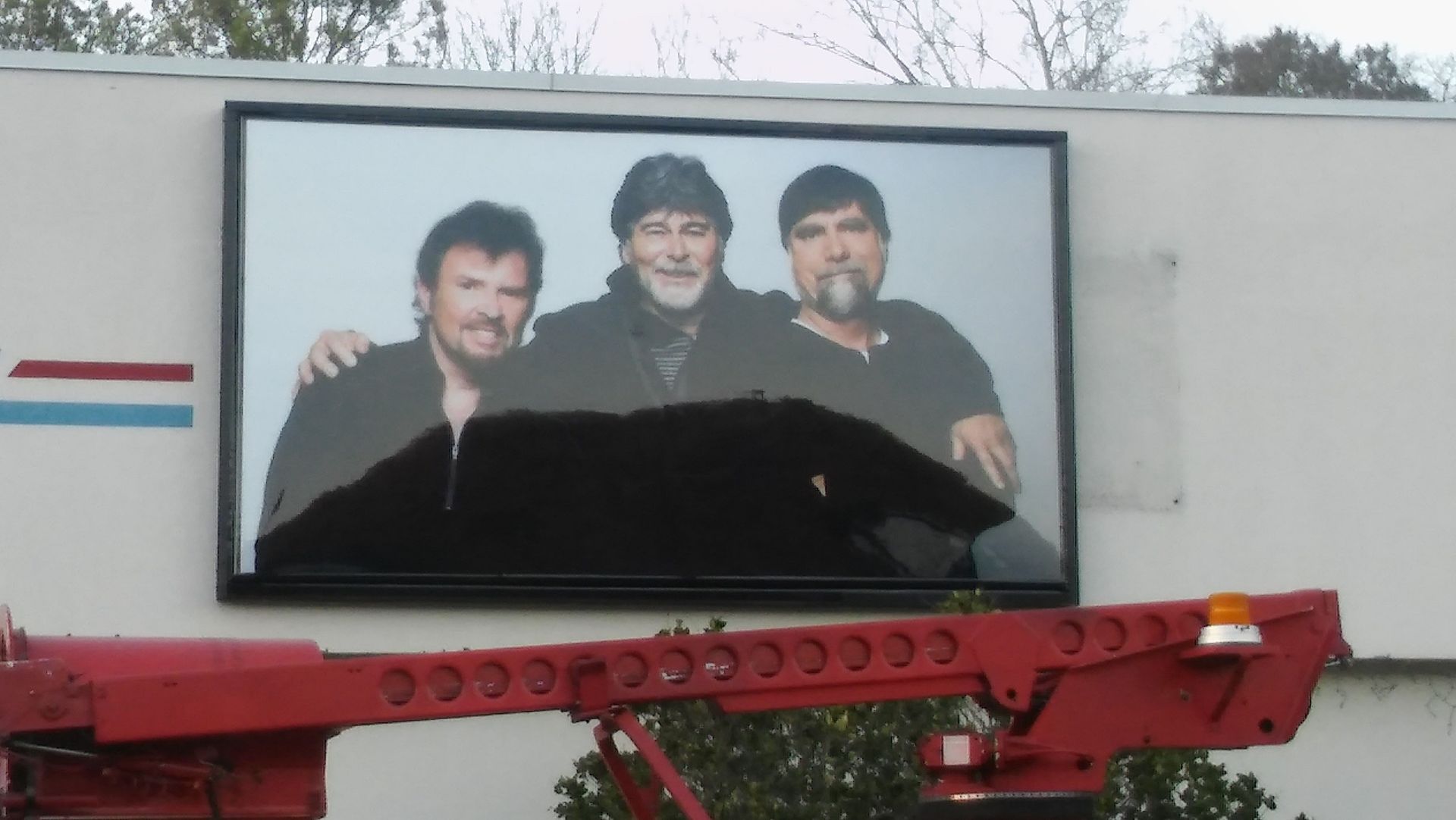 A picture of three men is hanging on the side of a building