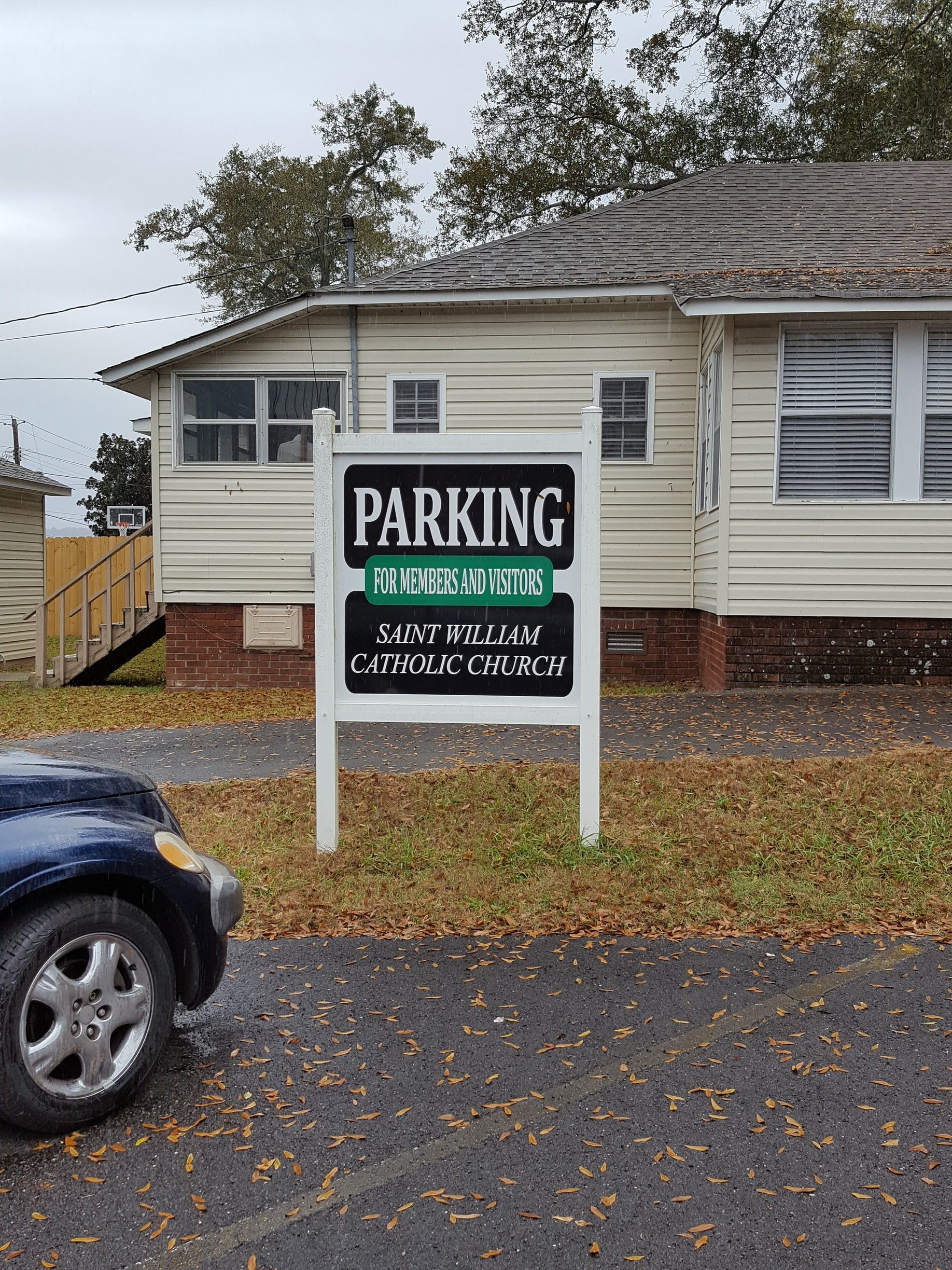 A car is parked in front of a house with a parking sign in front of it.