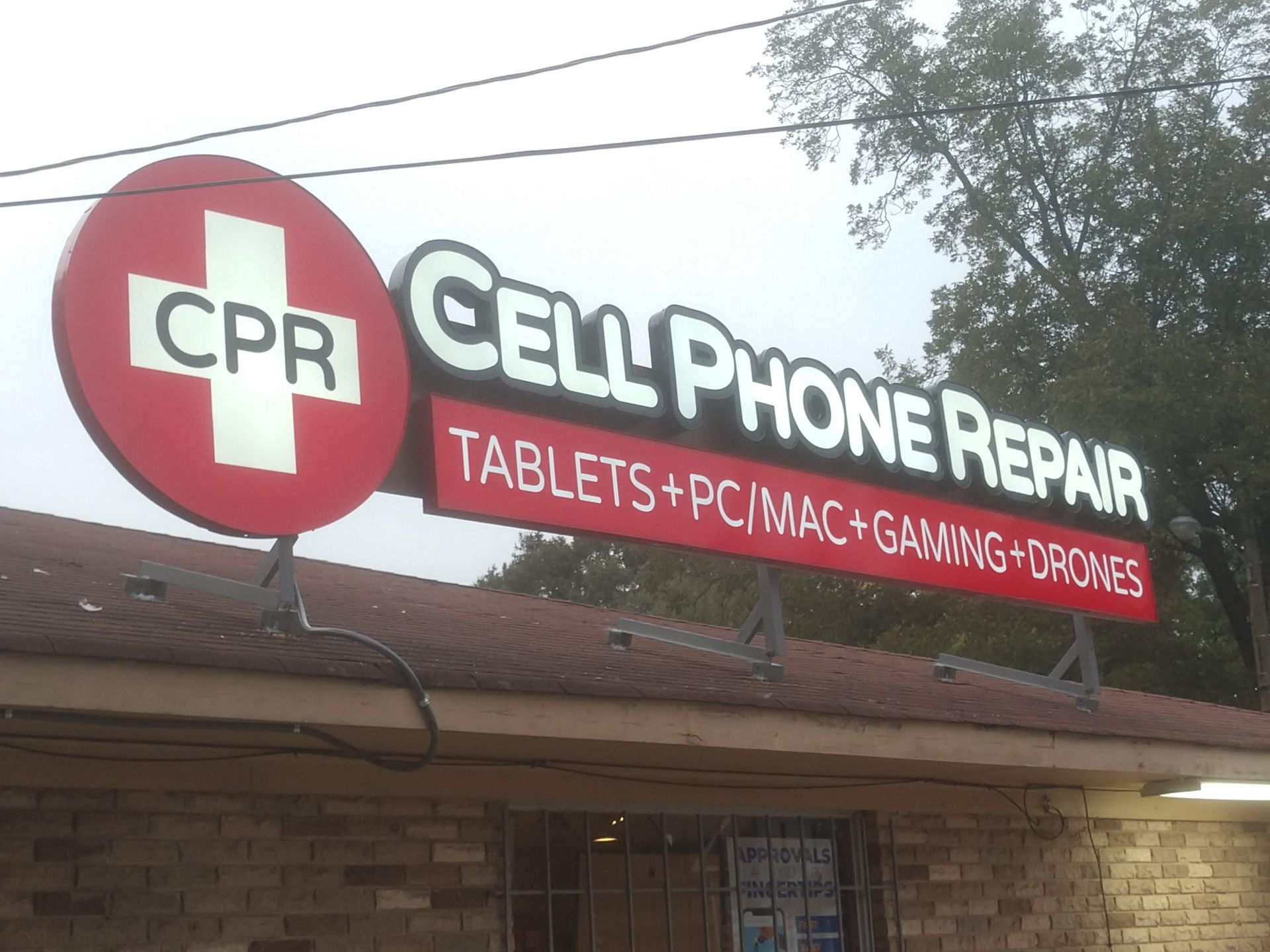 A cpr cell phone repair sign hangs from the side of a building