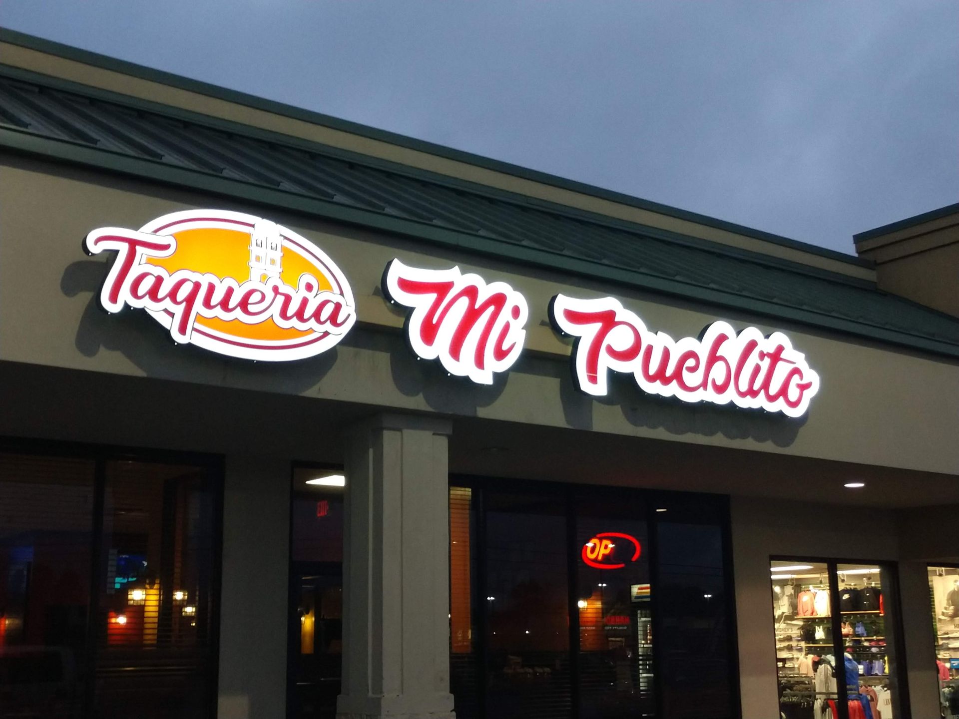 A restaurant called taqueria mi pueblito is lit up at night