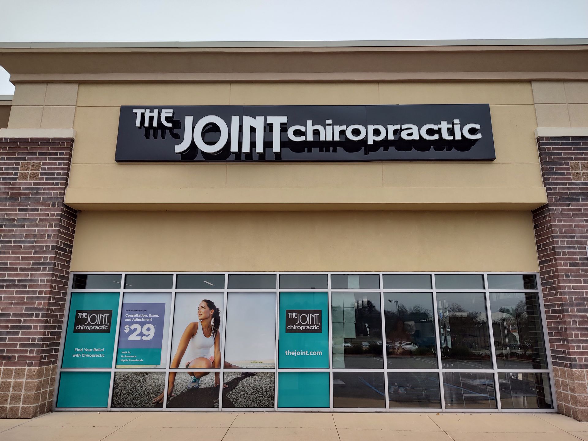 The front of a joint chiropractic store with a woman sitting on a bike