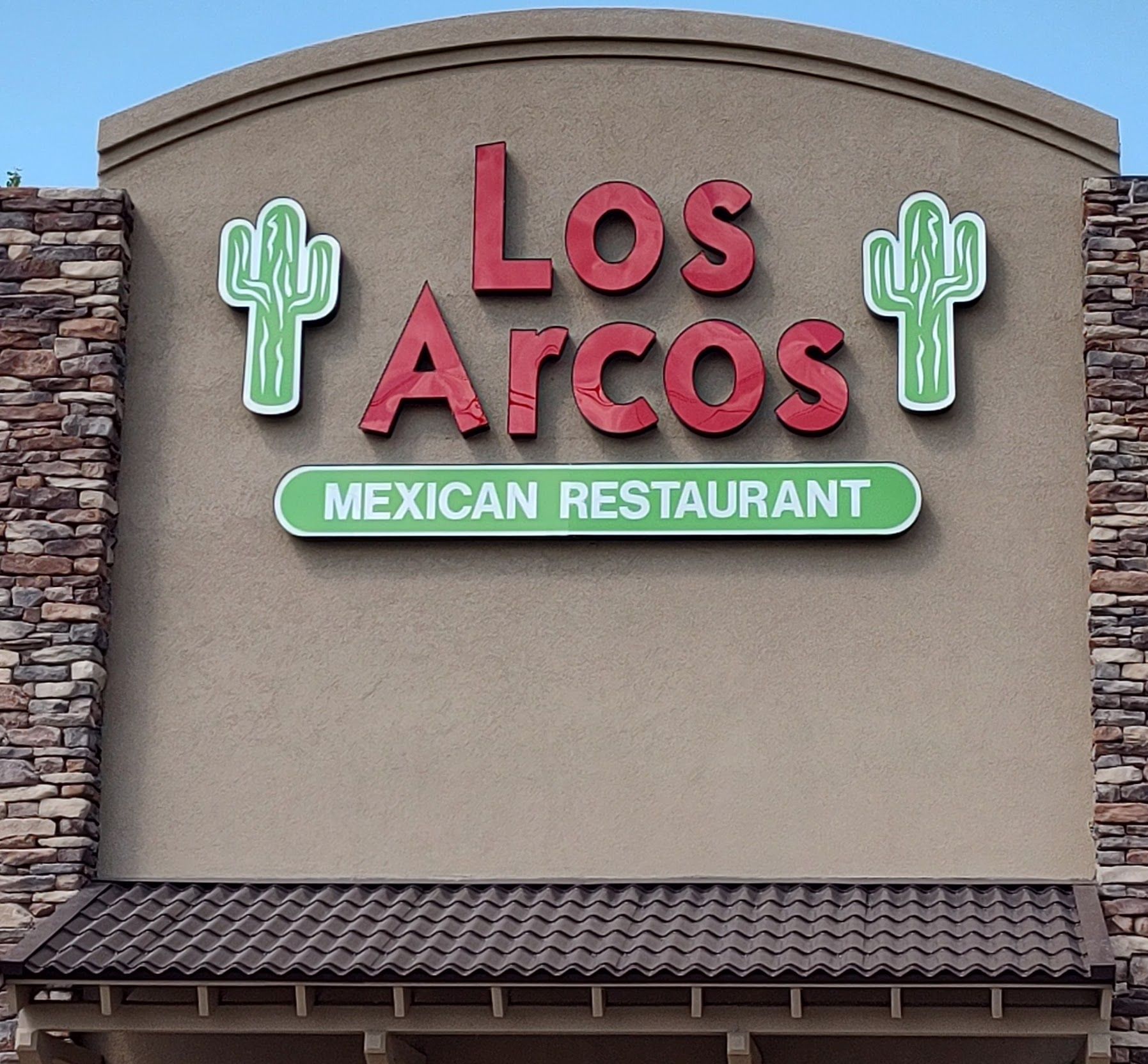 Sign for Los Arcos Mexican Restaurant with red letters and green cactus images.