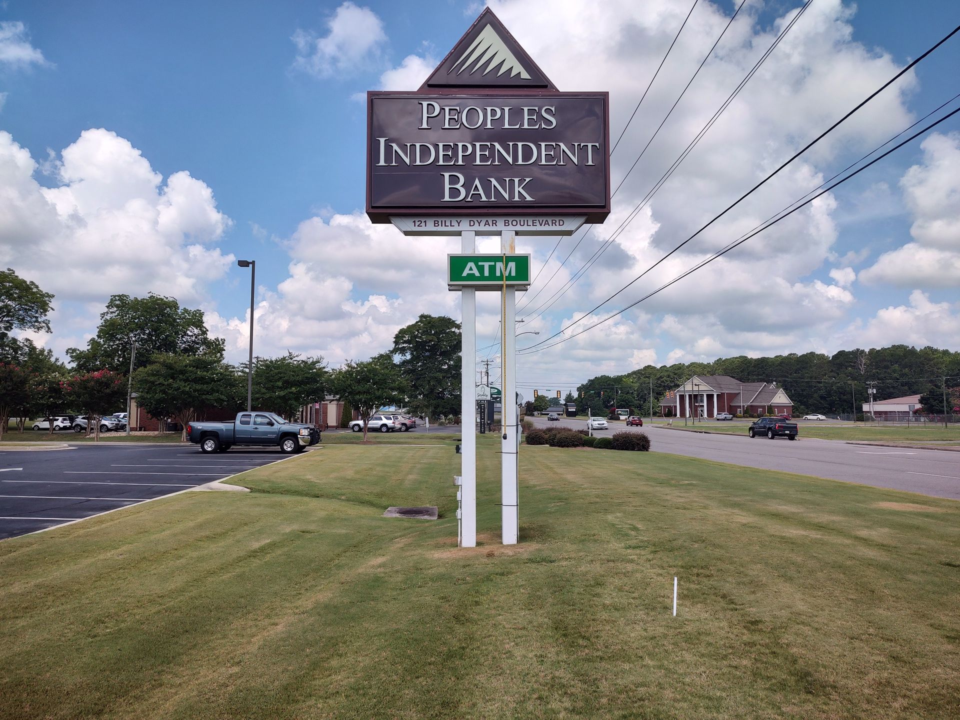 A sign for the peoples independent bank sits in the middle of a grassy field