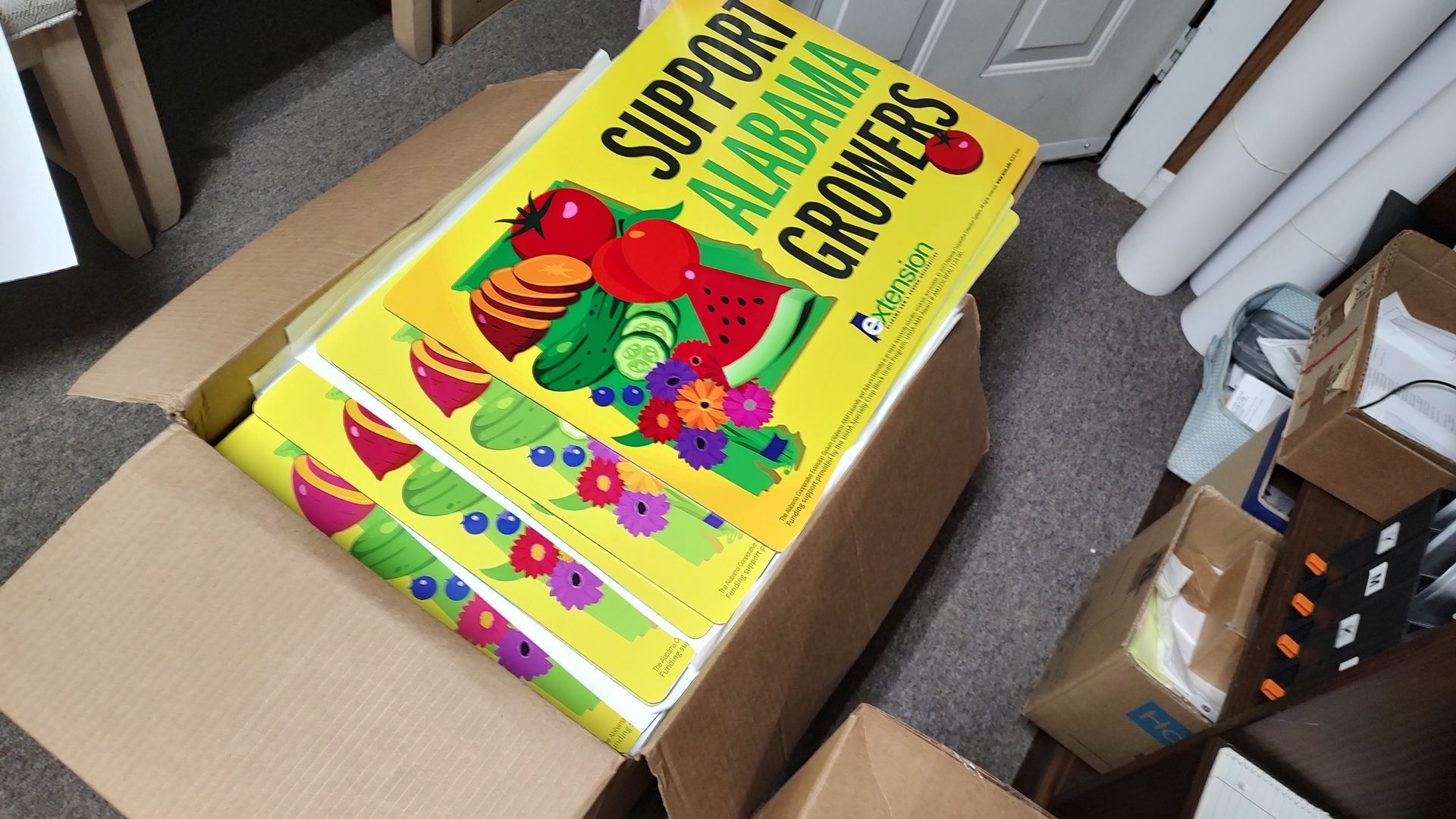 A box with a yellow sign that says support alabama growers