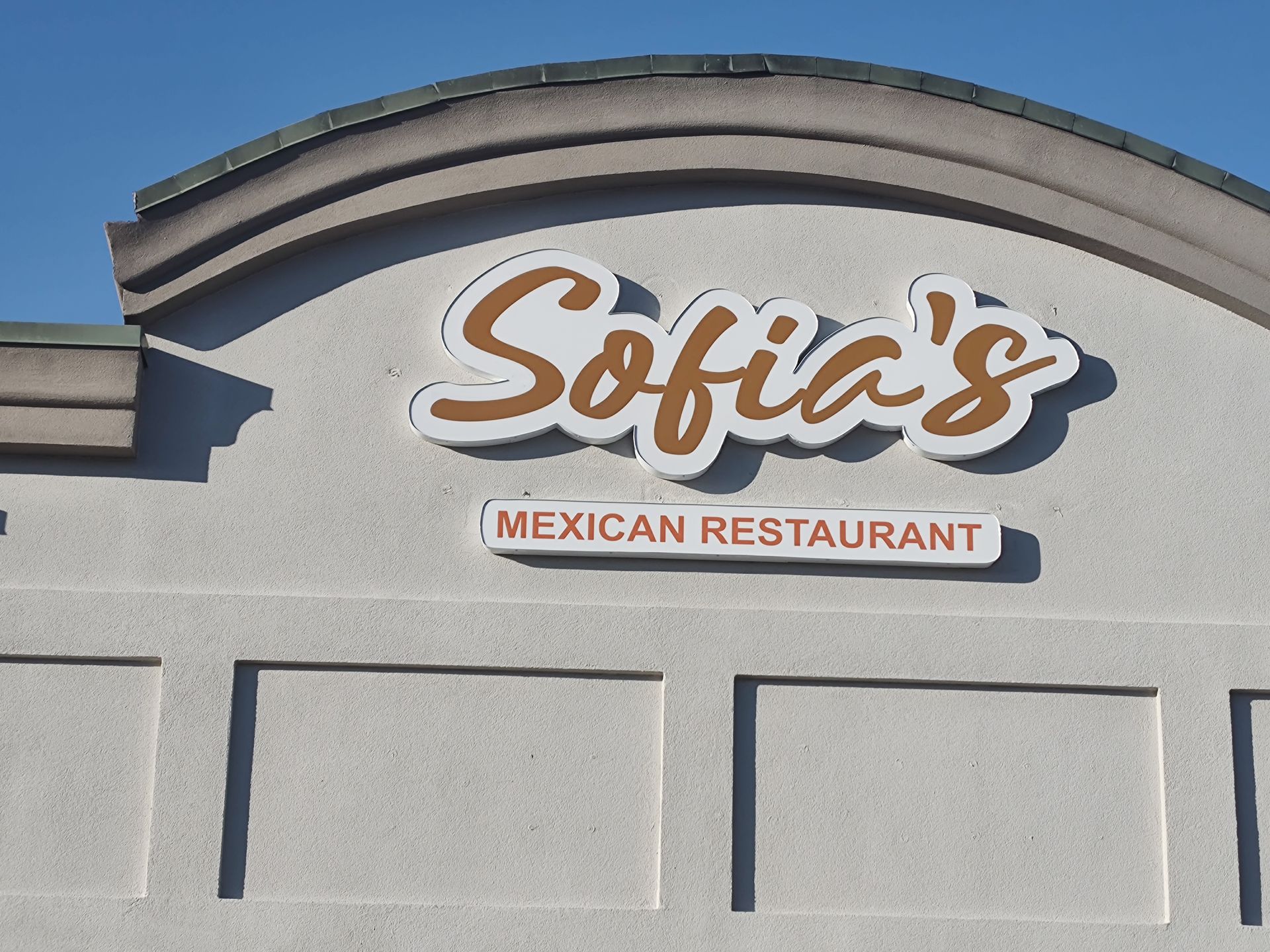 Sofia's Mexican Restaurant sign on a stucco building with a blue sky background.