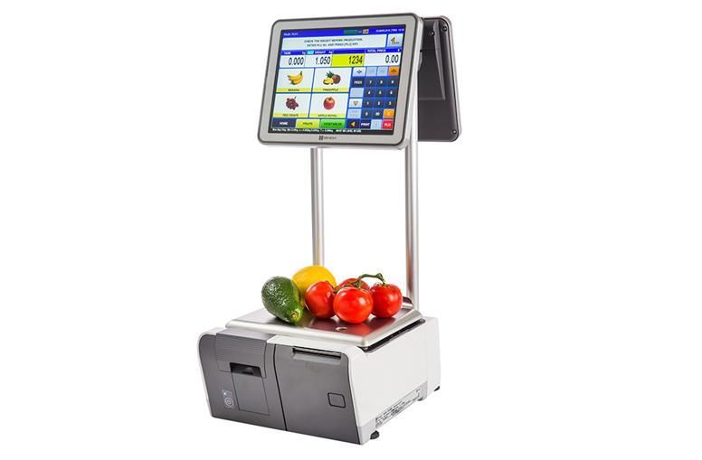 A digital scale at a grocery store, with a touchscreen displaying fruit pricing and produce on its weighing plate.