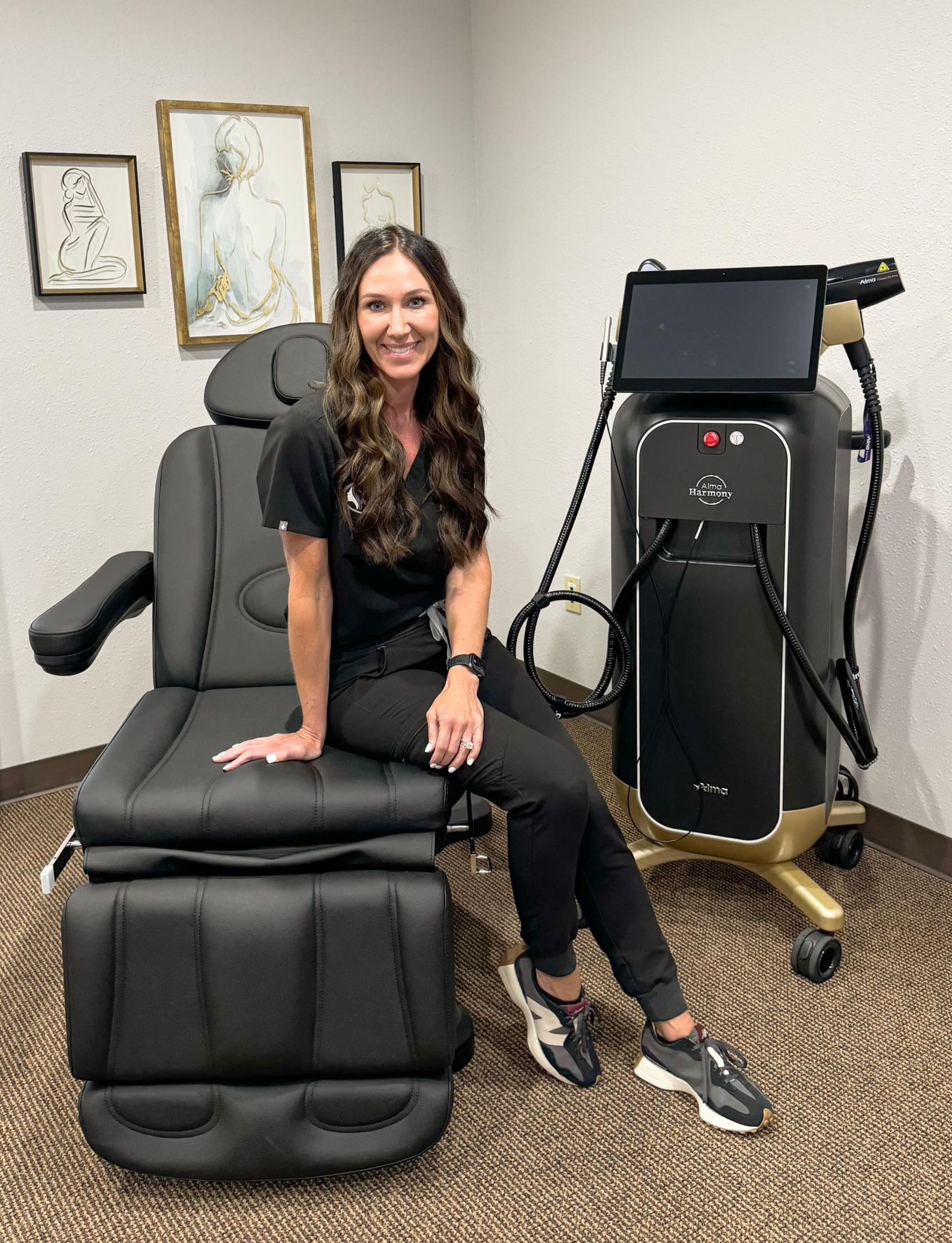 Woman seated on a black massage chair beside a medical device in a clinic room