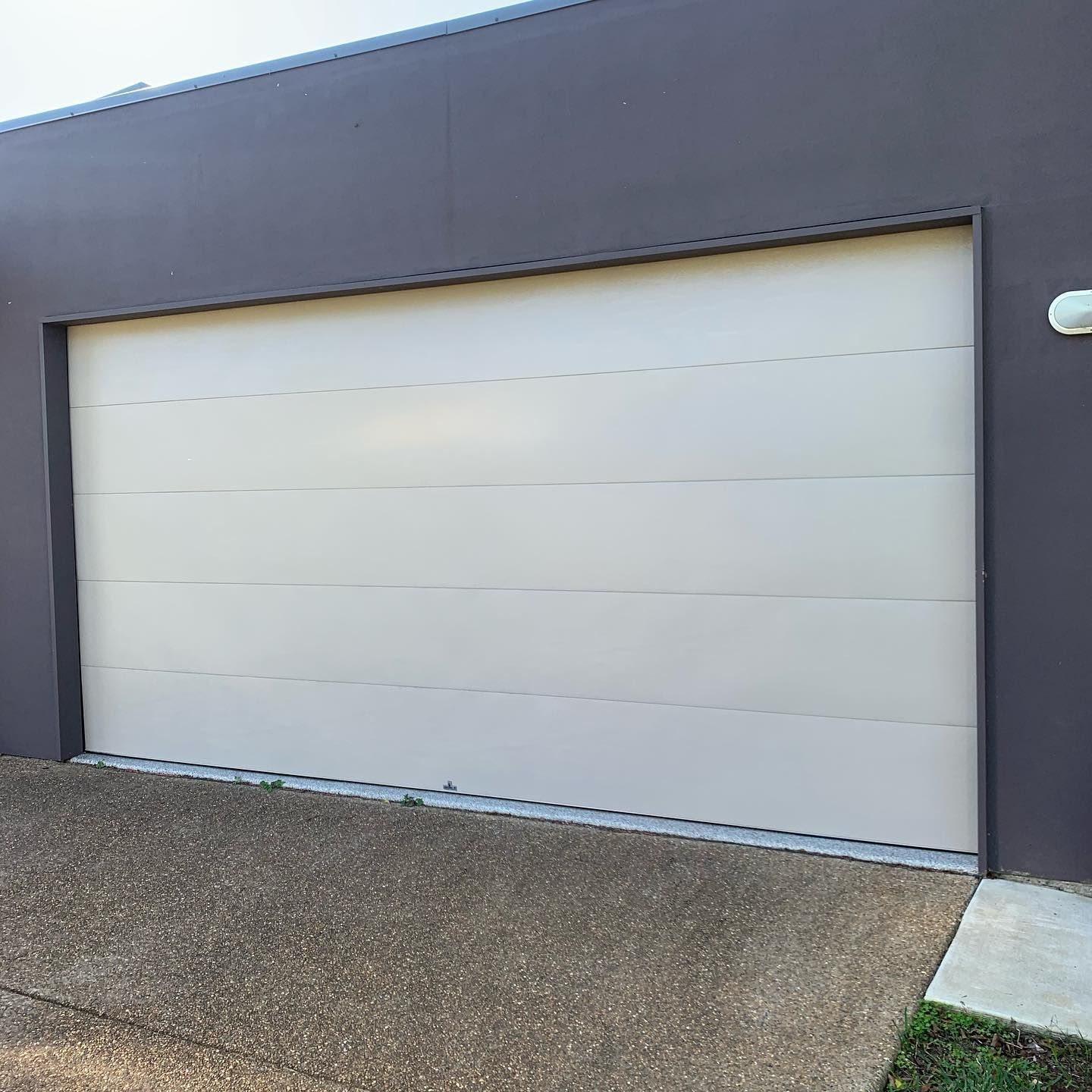 A white garage door is sitting on the side of a building.