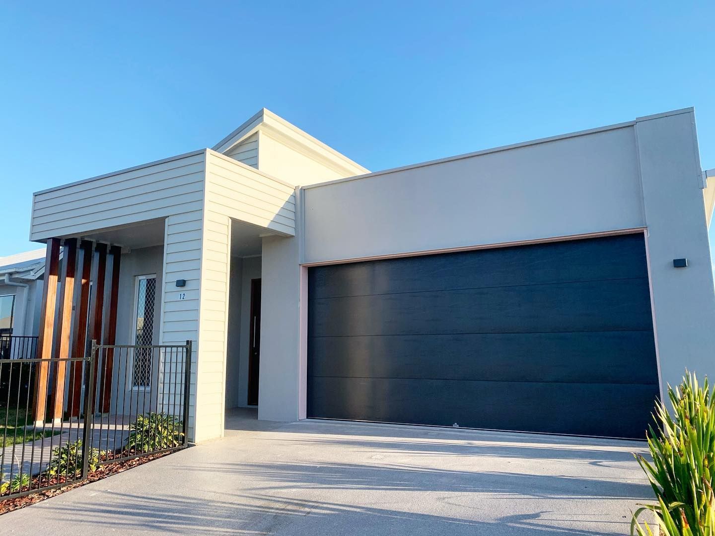A modern white house with a black garage door.
