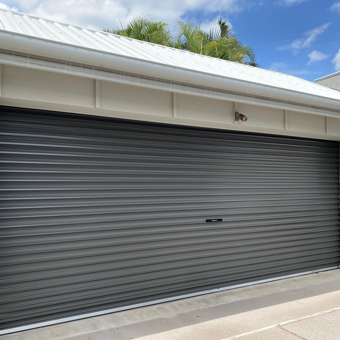 A garage with a gray garage door and a white roof.