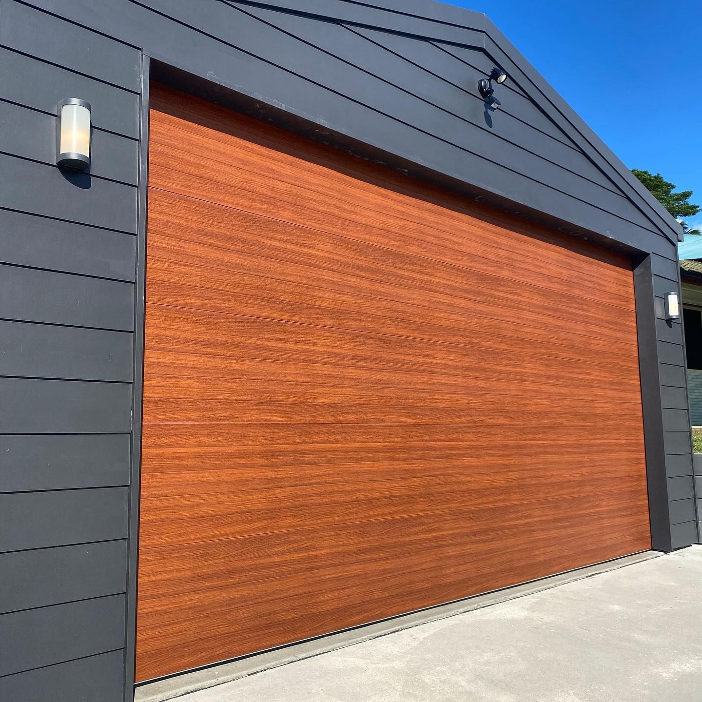 A garage with a wooden door and a black siding