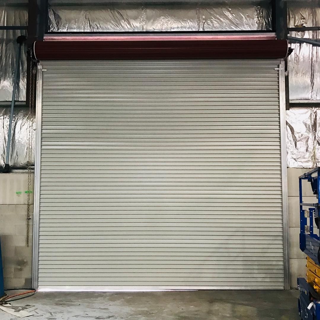 A white roller shutter door is open in a warehouse.