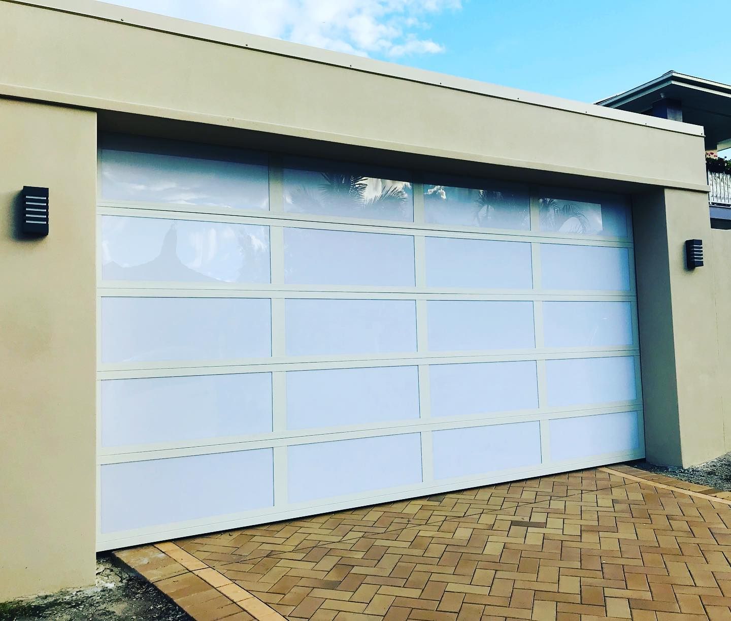 A white garage door is sitting on a brick driveway.