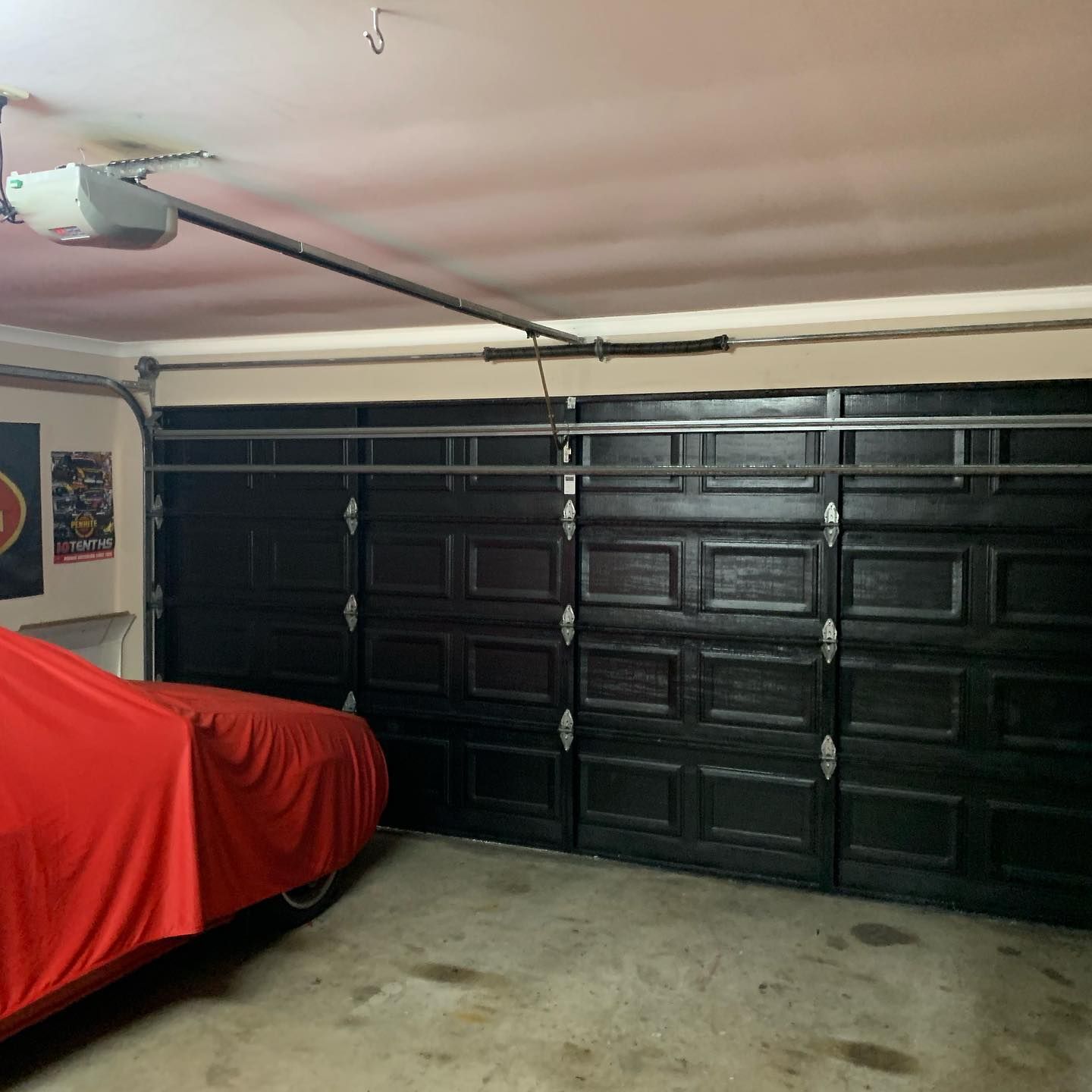 A red car is parked in a garage with black doors