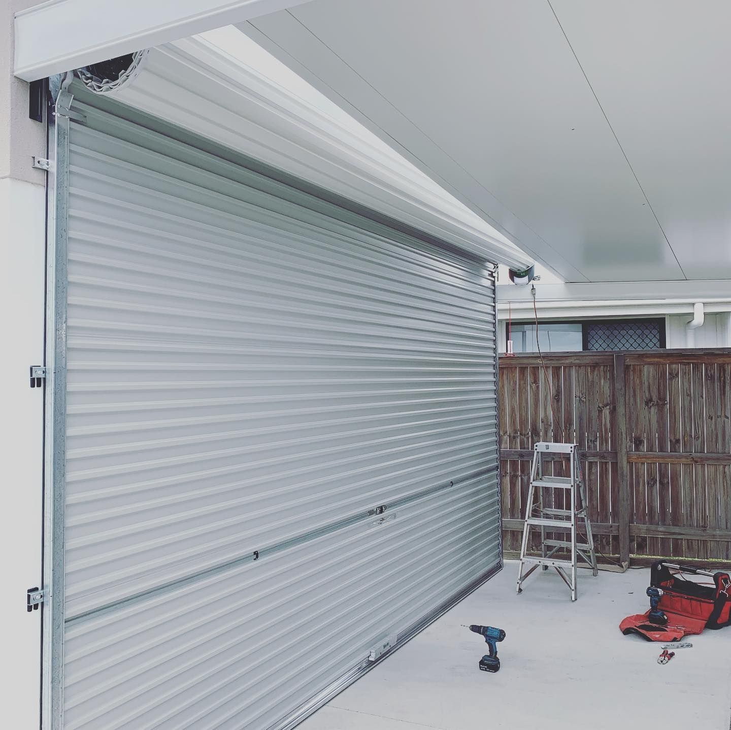 A garage door is being installed with tools and a ladder