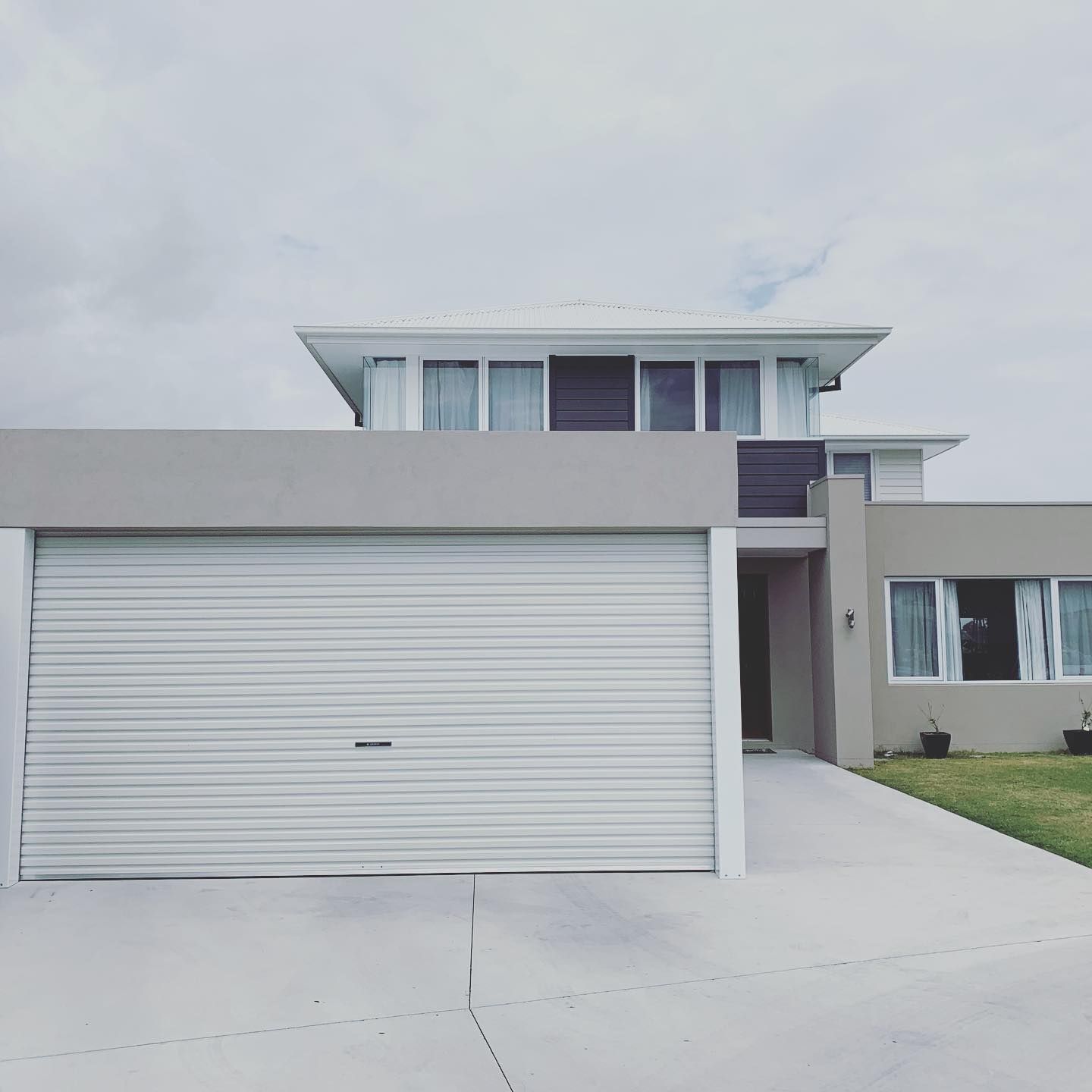 A modern house with a white garage door and a driveway.