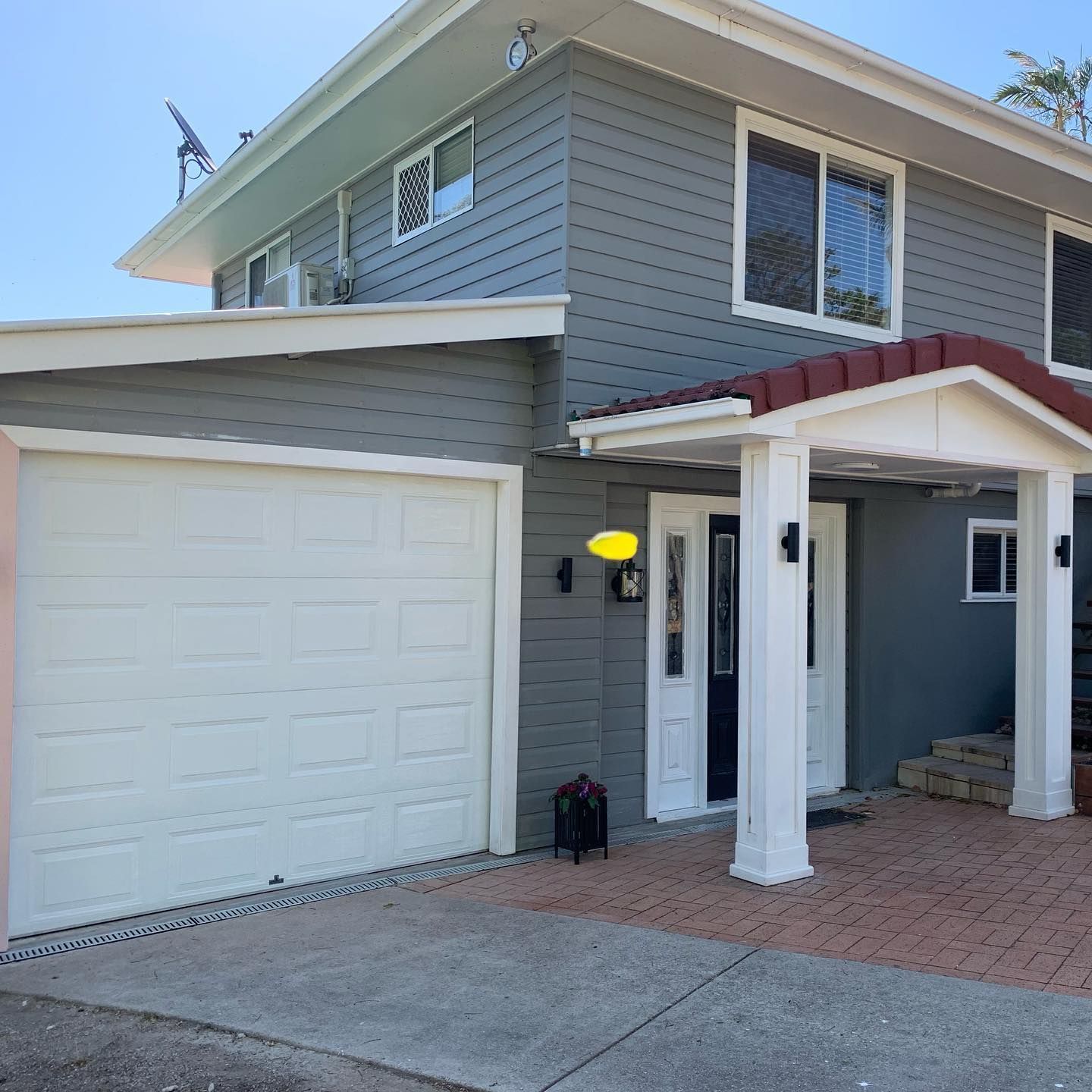 A gray house with a white garage door and a red roof