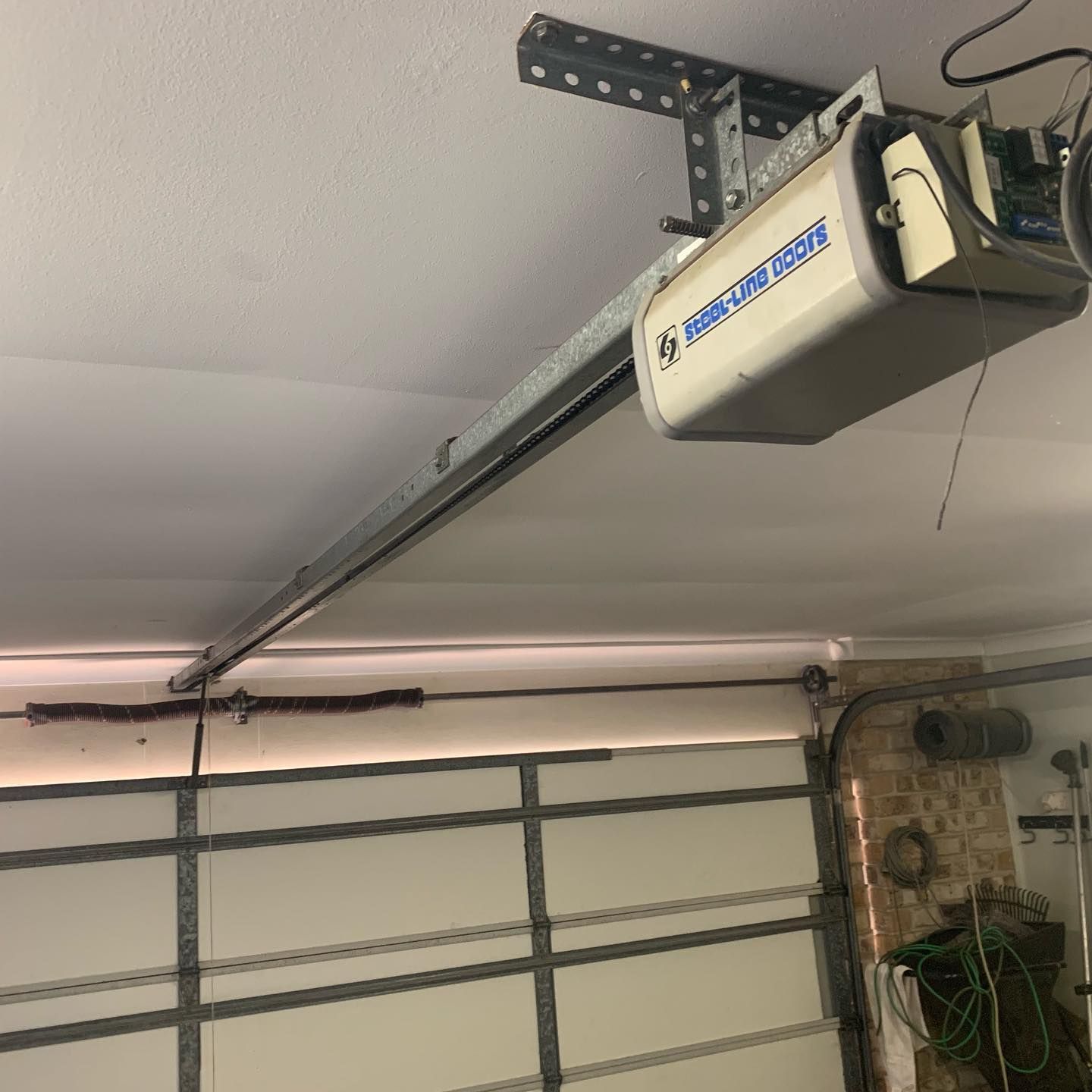 A garage door opener is hanging from the ceiling in a garage.