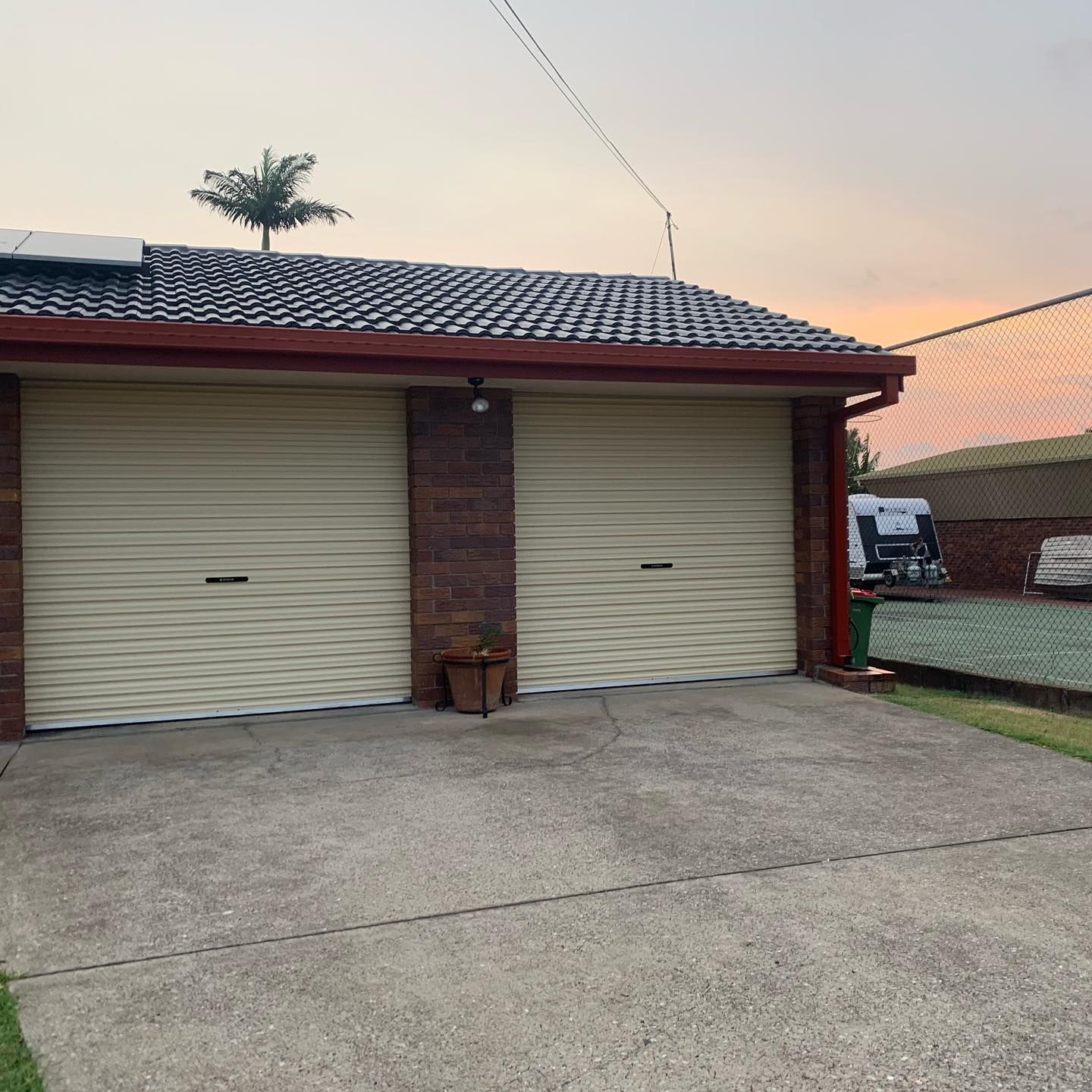 A garage with two white garage doors and a brick wall.
