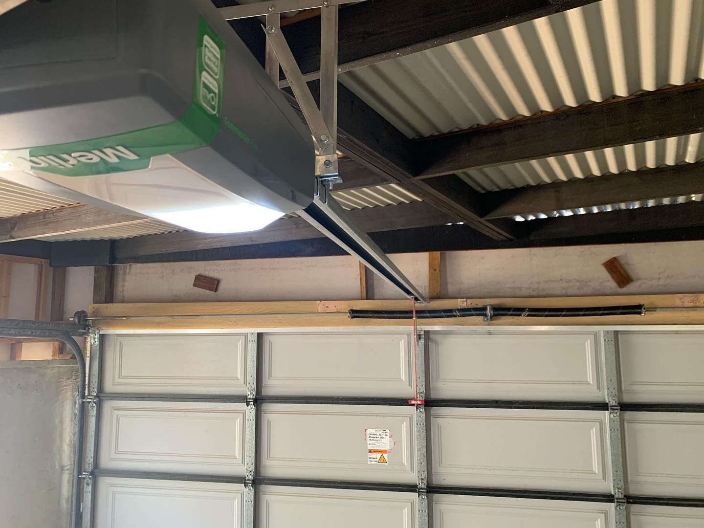 A garage door opener is hanging from the ceiling above a garage door.