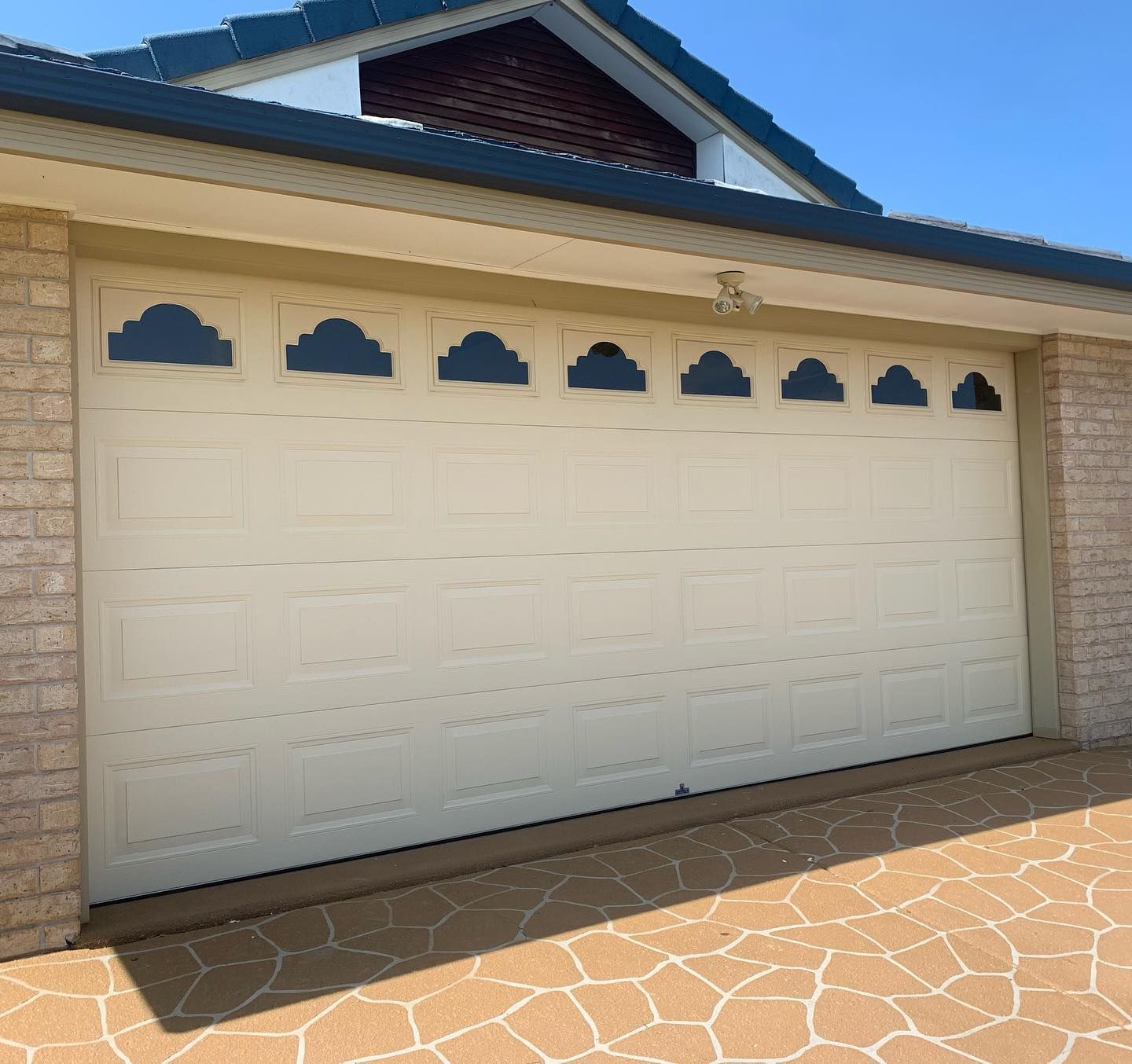 A white garage door with black clouds on it is in front of a brick building.