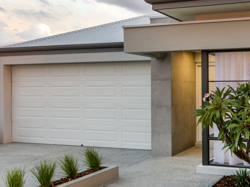 A house with a white garage door and a tree in front of it