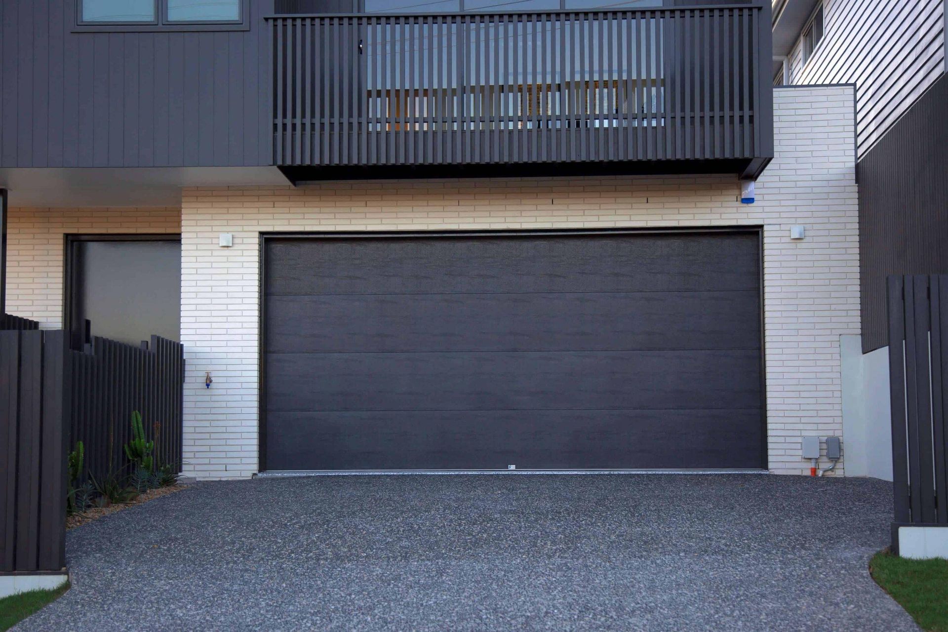 A black garage door is sitting in front of a house.