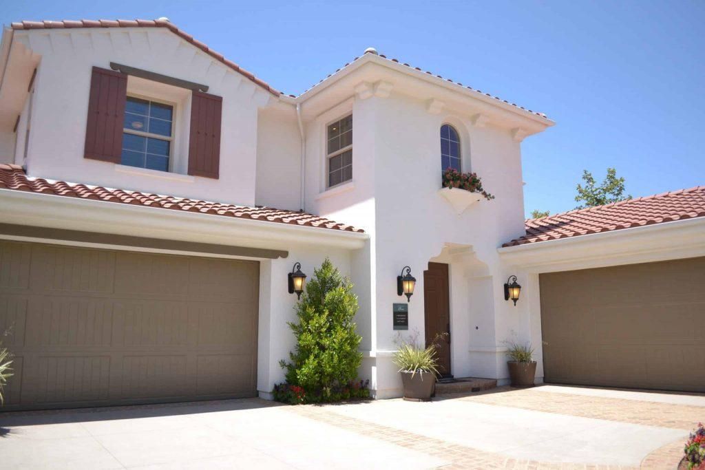 A white house with three garage doors and a driveway