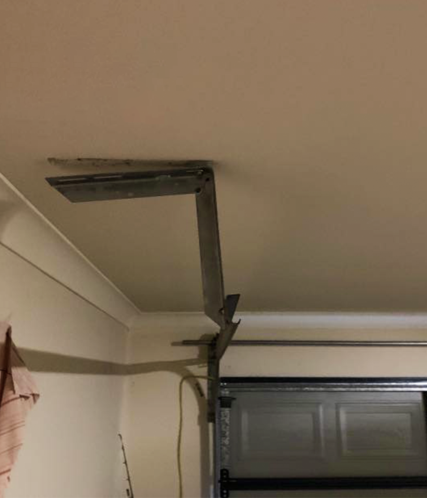 A garage door opener is hanging from the ceiling in a garage.