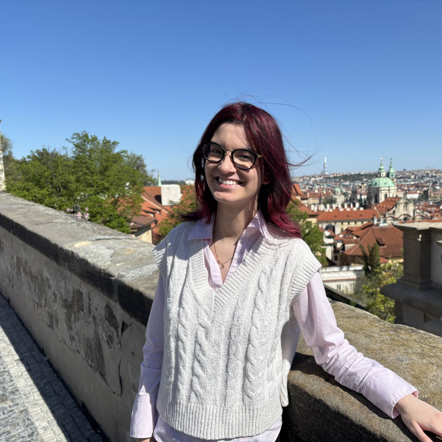A woman with dyed teal hair and eyeglasses is smiling for the camera.