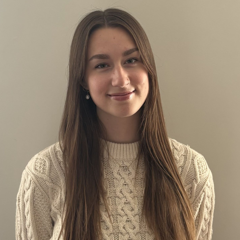 A woman wearing a white knit sweater is smiling for the camera.