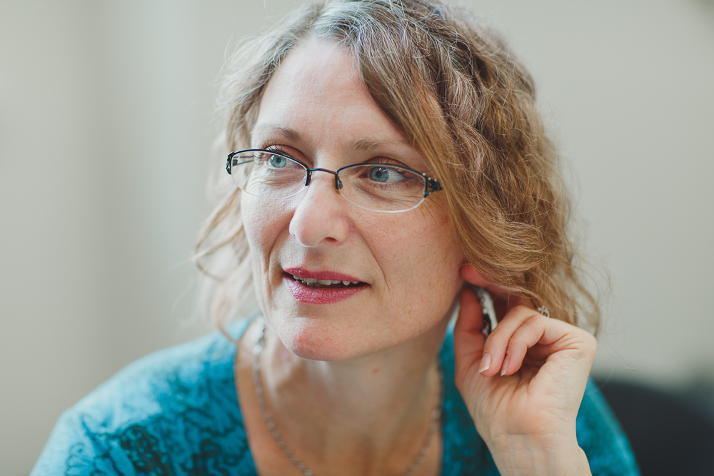 A close up of a woman wearing glasses and a blue shirt