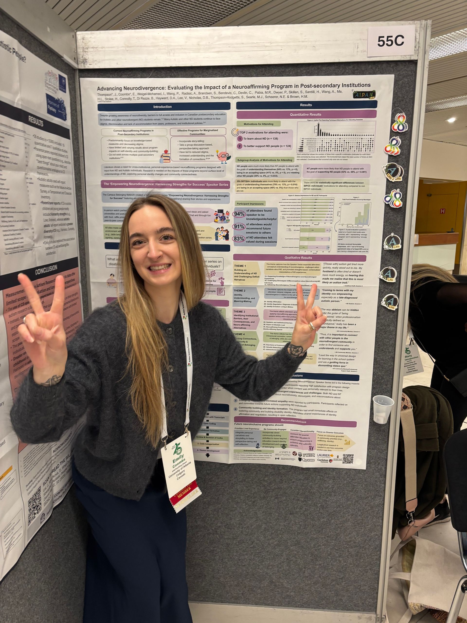 Woman posing with peace signs beside a colorful academic poster at a conference.