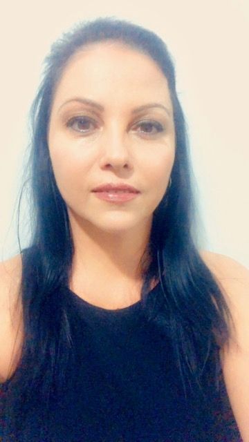 Portrait of a person with long dark hair wearing a black top against a light background