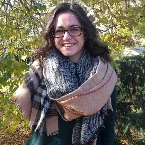 A woman wearing glasses and a scarf is smiling for the camera.