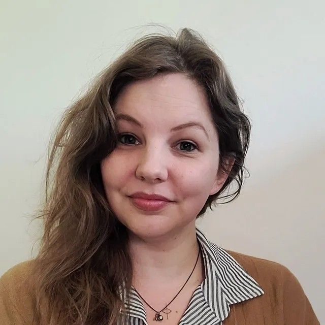 A woman wearing a necklace and earrings is smiling for the camera.
