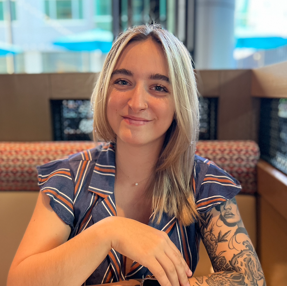 A woman with a tattoo on her arm is sitting at a table in a restaurant.