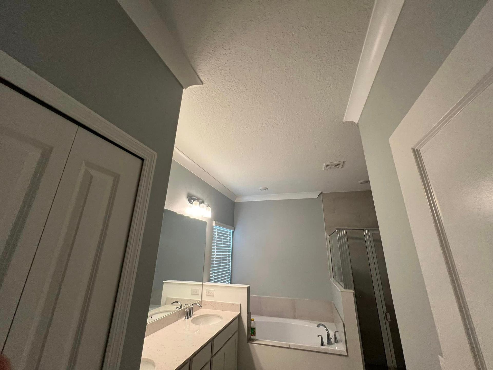 A bathroom with two sinks , a tub , and a mirror.