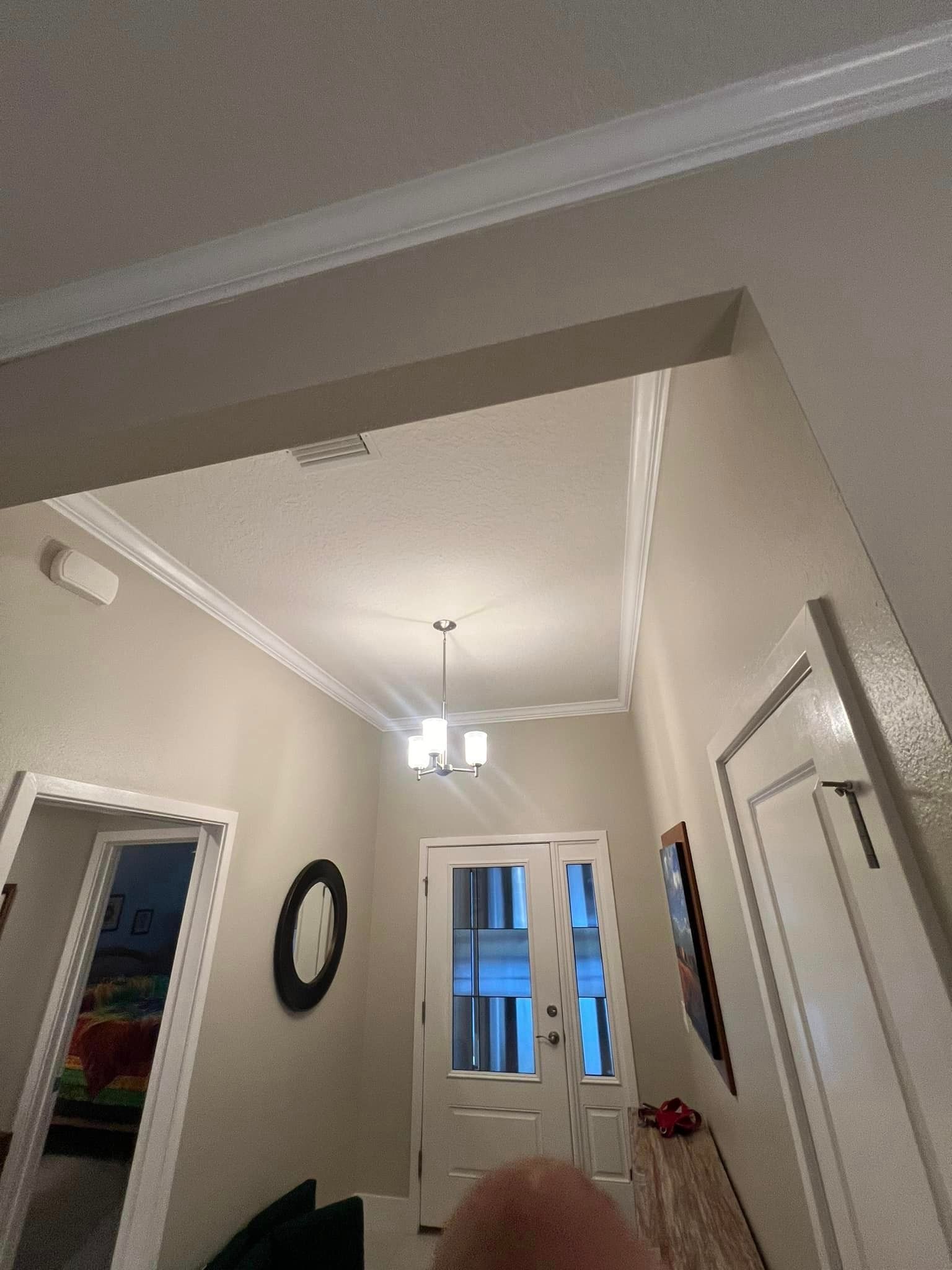 A hallway with a chandelier hanging from the ceiling and a mirror on the wall.