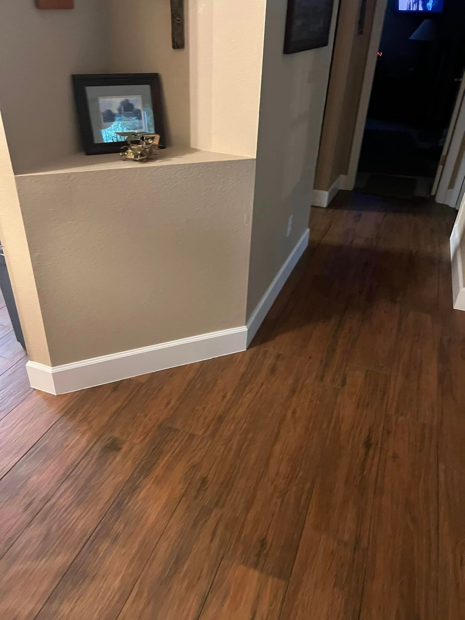 A hallway with hardwood floors and a picture on the wall.