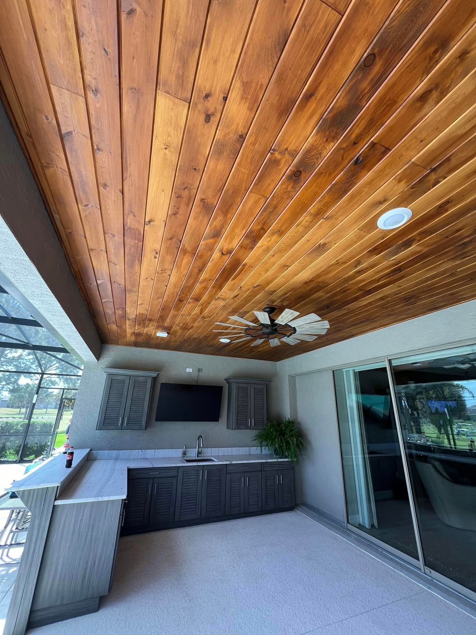 A kitchen with a wooden ceiling and a ceiling fan.