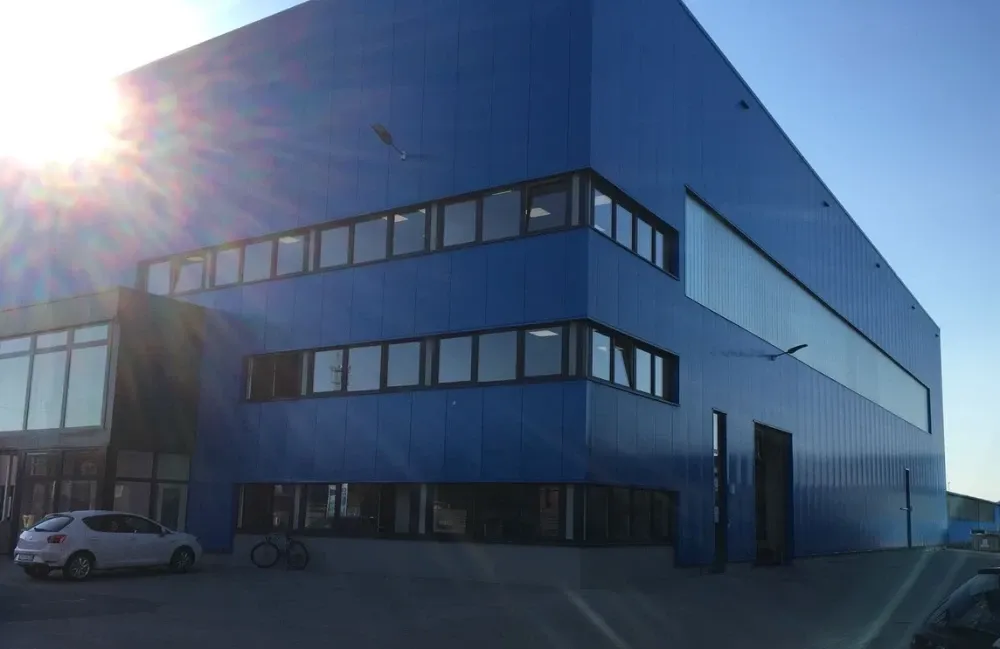 Ein blaues Gebäude mit vielen Fenstern und einem davor geparkten Auto.